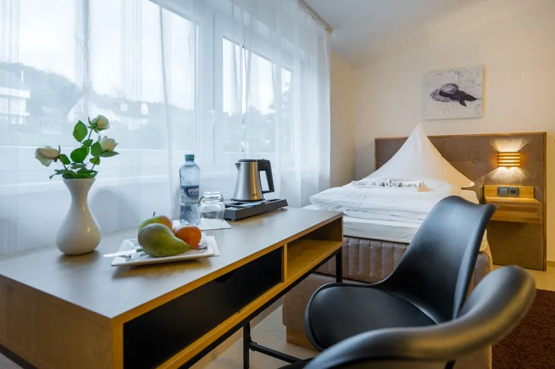 Schreibtisch am Fenster, dahinter das Bett